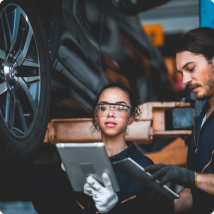 Two young techs using tablets to repair a vehicle on a lift